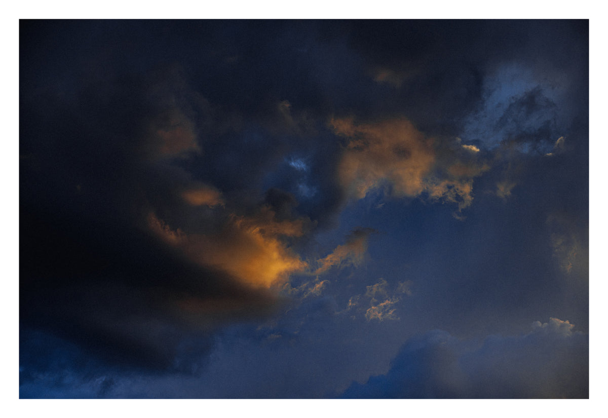 A dense Alberta sky under dramatic light. Shown with the white signing border.