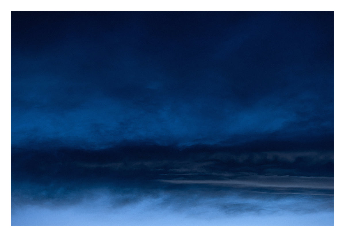 An Alberta sky forming distant, familiar landscapes out of cloud. Shown with the white signing border.