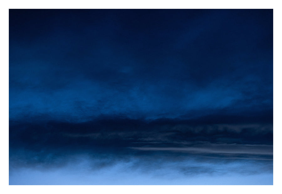 An Alberta sky forming distant, familiar landscapes out of cloud. Shown with the white signing border.
