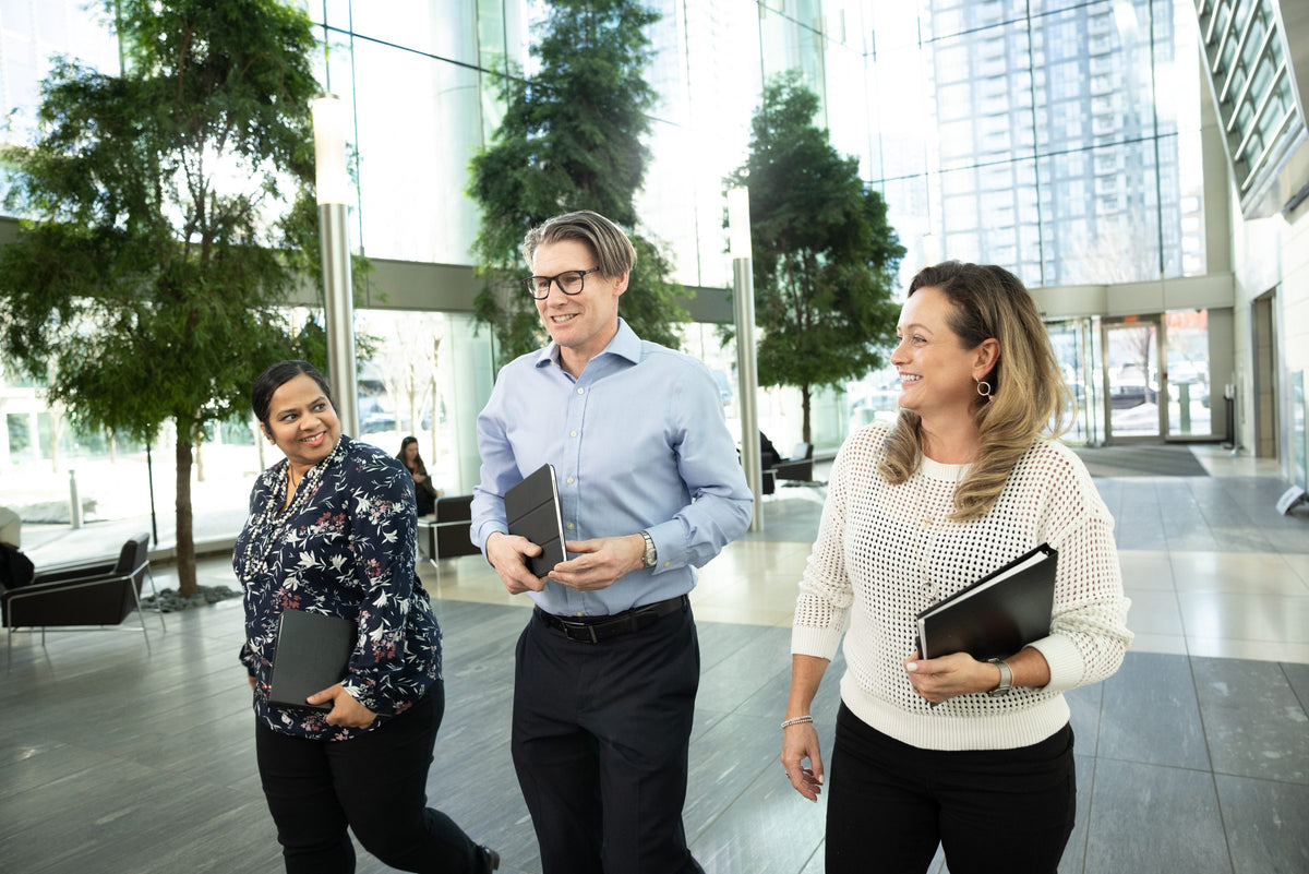 Three colleagues walking through a bright office atrium