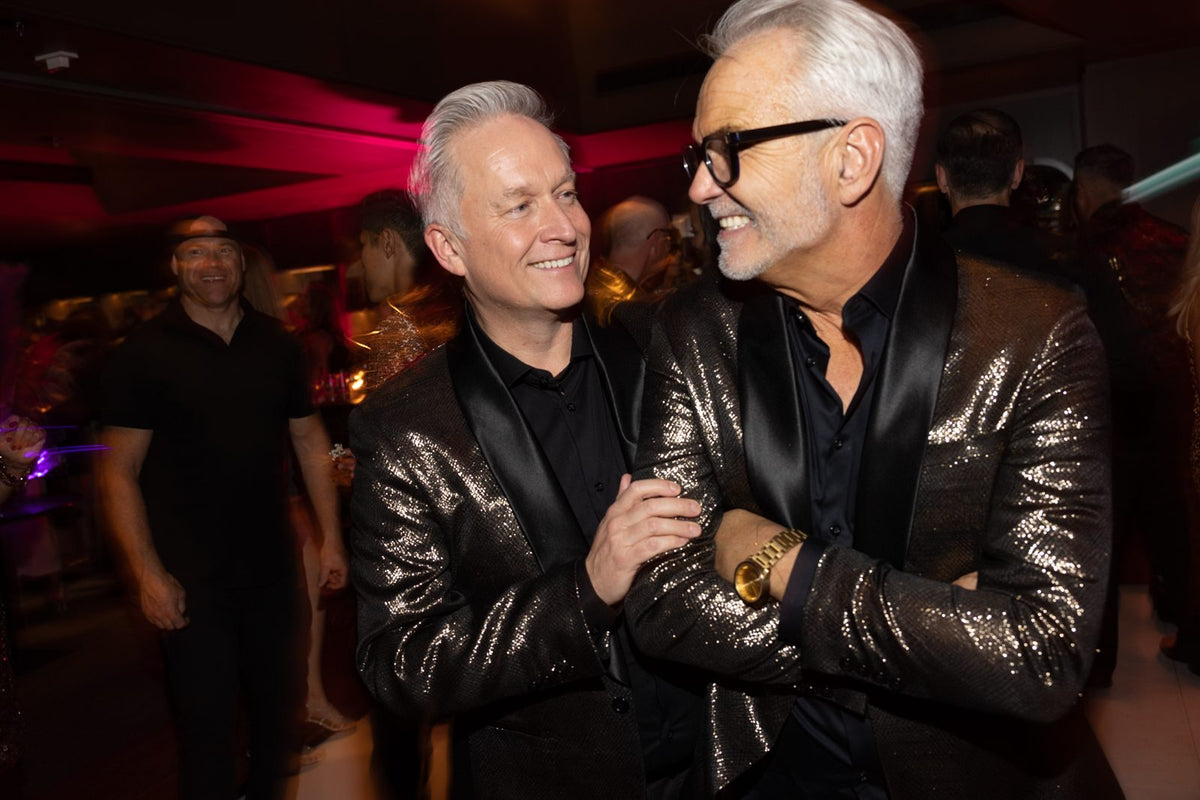 Two guests laughing together at an event, in sequin jackets